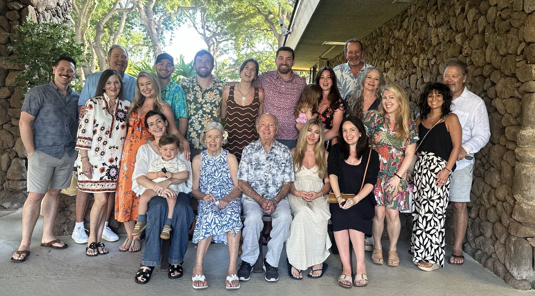 Jim and Janet seated at the center of the extended Hagan family, gathered under a lava rock archway in Maui